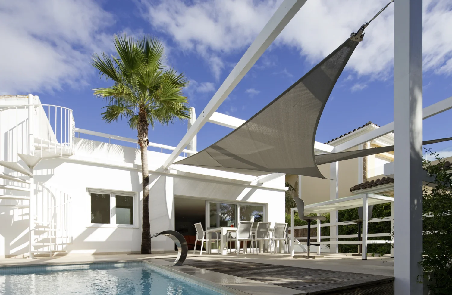 Moderne Terrasse mit Sonnensegel und Pool in sonniger Umgebung
