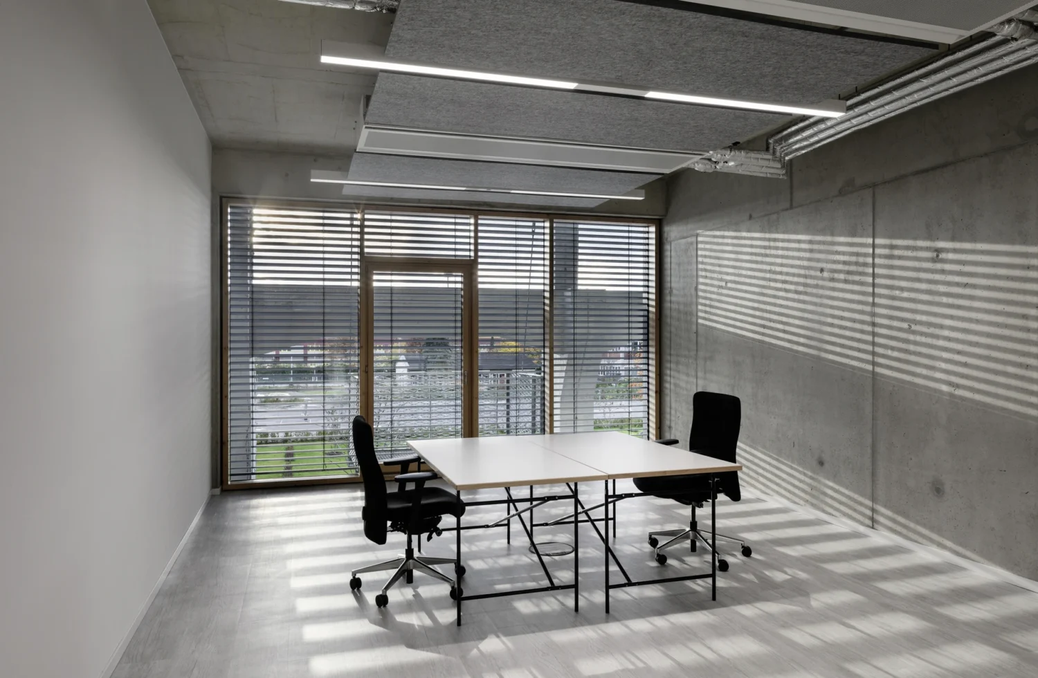 Modernes, minimalistisches Büro mit zwei Schreibtischen und Stühlen in einem lichtdurchfluteten Raum