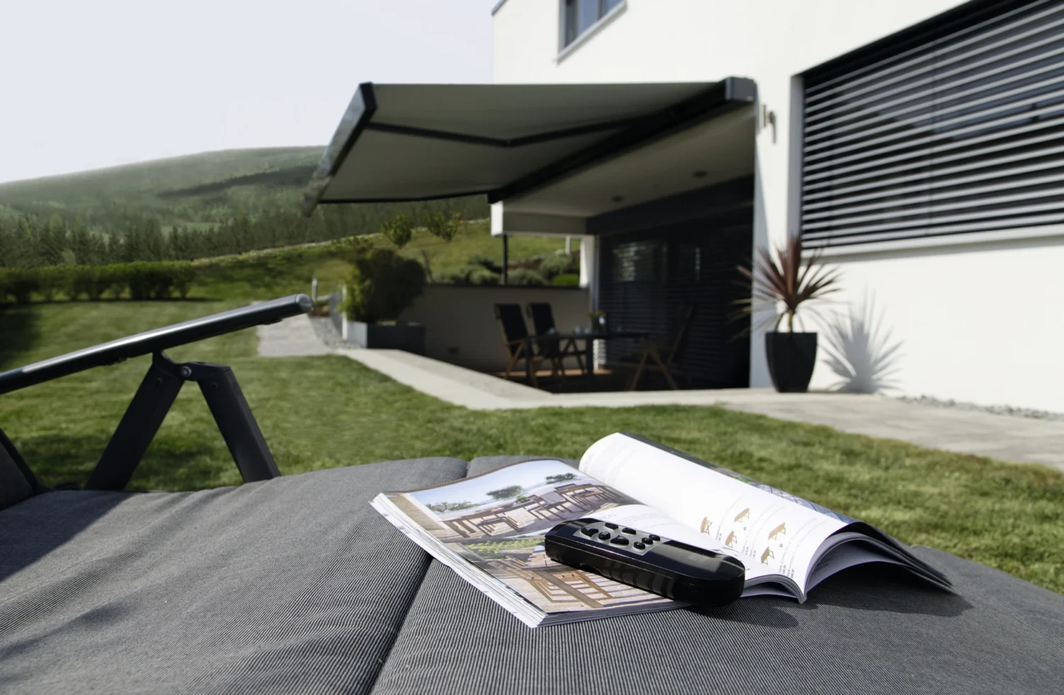 Moderne Terrasse mit Liegestuhl und Fernbedienung auf einem Tisch